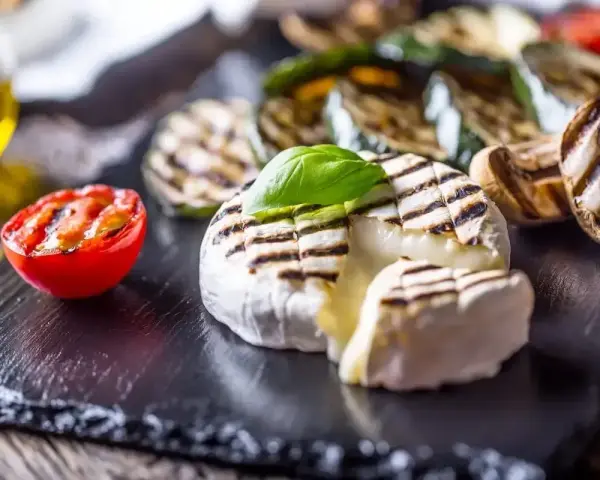 Pyszny camembert z grilla, z rumianymi paskami, podany z grillowanymi warzywami i pomidorkiem. Idealny na letnie wieczory.