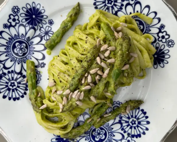 Makaron z zielonym pesto i szparagami, posypany pestkami słonecznika. Czy makaron jest zdrowy? Zależy od dodatków!
