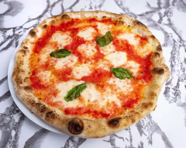 Pyszne ciasto na pizzę neapolitańską z sosem pomidorowym, mozzarellą i bazylią. Idealna na szybki lunch.