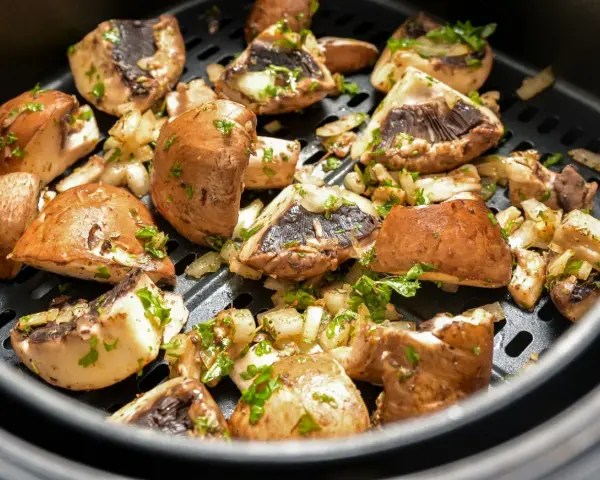 Pyszne pieczarki z airfryer, przyprawione i posypane natką pietruszki, gotowe do podania.
