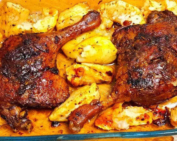 Pyszne, pieczone udka z kaczki z chrupiącymi ziemniakami, skąpane w aromatycznym sosie.