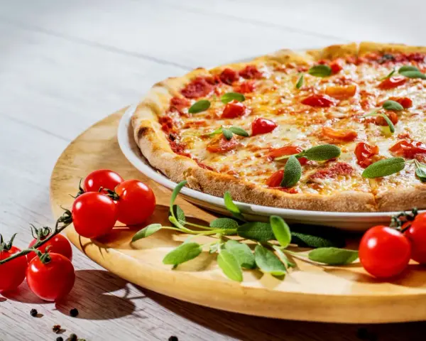Apetyczna pizza z pomidorkami i bazylią. Czy zastanawiałeś się, dlaczego pizza jest niezdrowa?