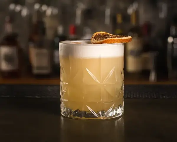 Klasyczny whisky sour przepis: orzeźwiający koktajl z pianką i plasterkiem suszonej pomarańczy. Idealny na każdą okazję.