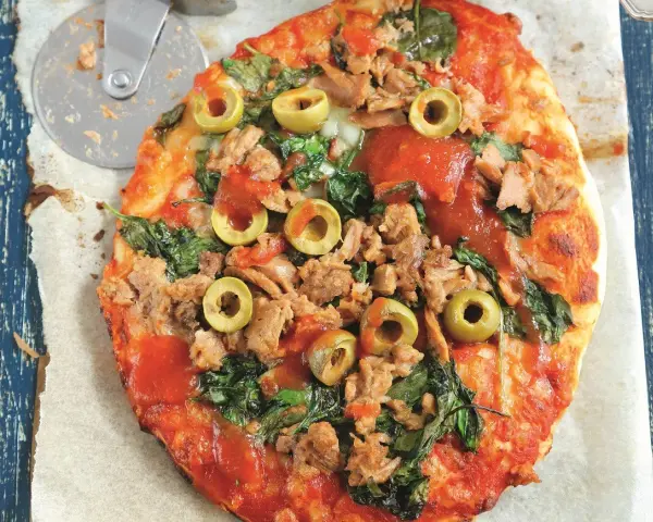 Pyszna pizza z tuńczykiem, szpinakiem i oliwkami, gotowa do pokrojenia.