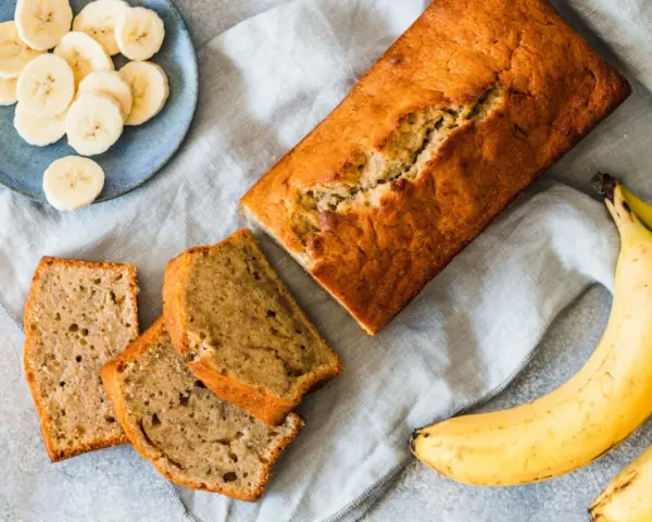 Pyszny, domowy chlebek bananowy – sprawdzony przepis na wilgotne ciasto. Obok kromki i plasterki banana.