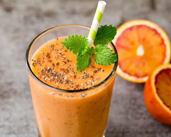 Pomarańczowy smoothie z nasionami chia i siemieniem lnianym, ozdobione miętą. Idealne na zdrowe śniadanie. Inspiracja na smoothie przepisy.