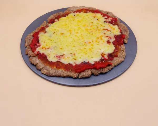 Pizza z chleba tostowego z sosem pomidorowym i roztopionym serem na ciemnej tacy.