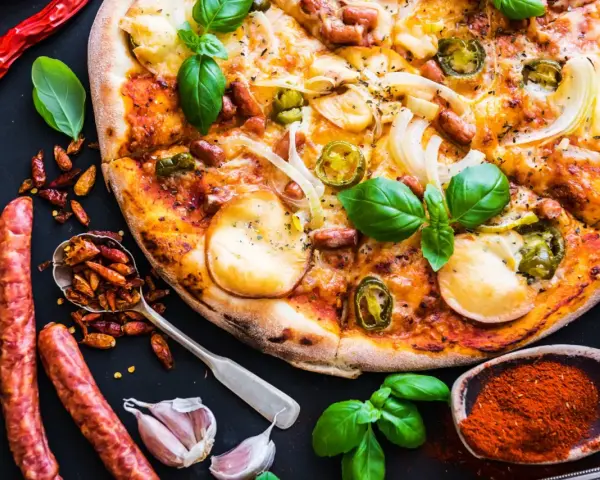 Apetyczna pizza z kiełbasą, cebulą i papryczkami jalapeño, otoczona składnikami.