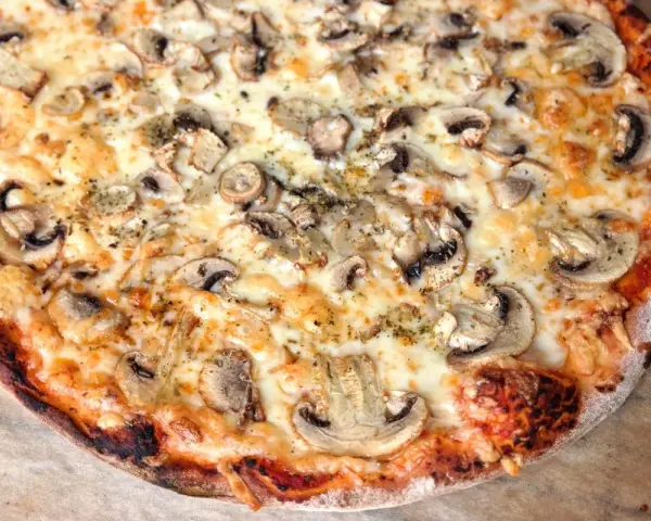 Pyszna pizza włoska z pieczarkami i ciągnącym serem. Idealny przepis na domową ucztę.