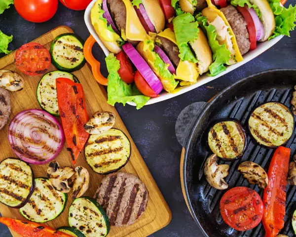 Pyszne przekąski na grilla: burgery, grillowane warzywa (cukinia, bakłażan, papryka, cebula, pomidory) i pieczarki. Idealne na letnie spotkania.