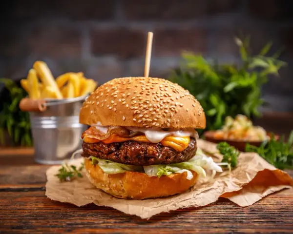 Pyszny burger z serem, bekonem i sałatą, idealny jako dodatek do frytek.
