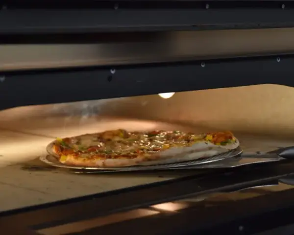 Pieczenie pizzy w piecu. Czy pizzę można zamrozić? Ta gorąca, parująca pizza na łopacie sugeruje, że świeżość jest kluczowa.