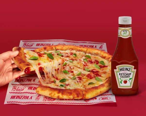 Ciepła pizza z ciągnącym serem i bazylią, obok butelka łagodnego ketchupu Heinz – idealny duet do każdego kęsa.