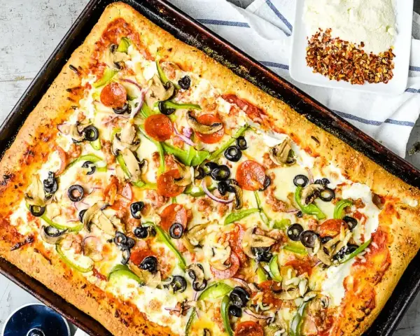 Pyszna pizza domowa na blachę z pieczarkami, papryką, oliwkami i pepperoni. Idealny przepis na szybki obiad.