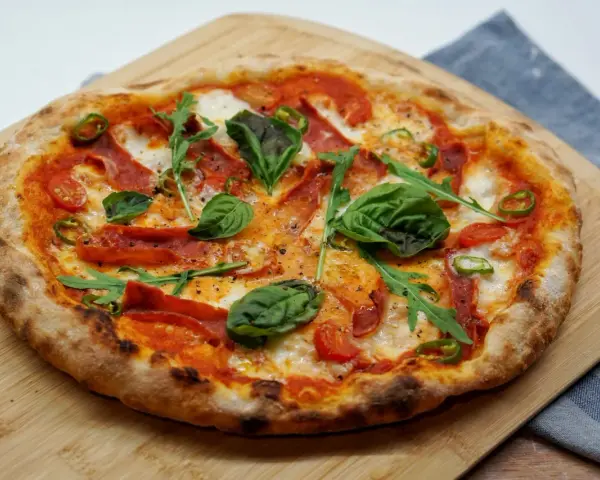 Pyszna pizza z rukolą, pomidorkami, papryczką i salami. Idealne składniki na pizzę, które zachwycą każdego smakosza.