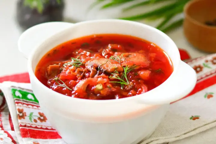 Aromaticzny barszcz ukraiński tradycyjny w białej miseczce, ozdobiony koperkiem. Idealny przepis na rozgrzewający obiad.