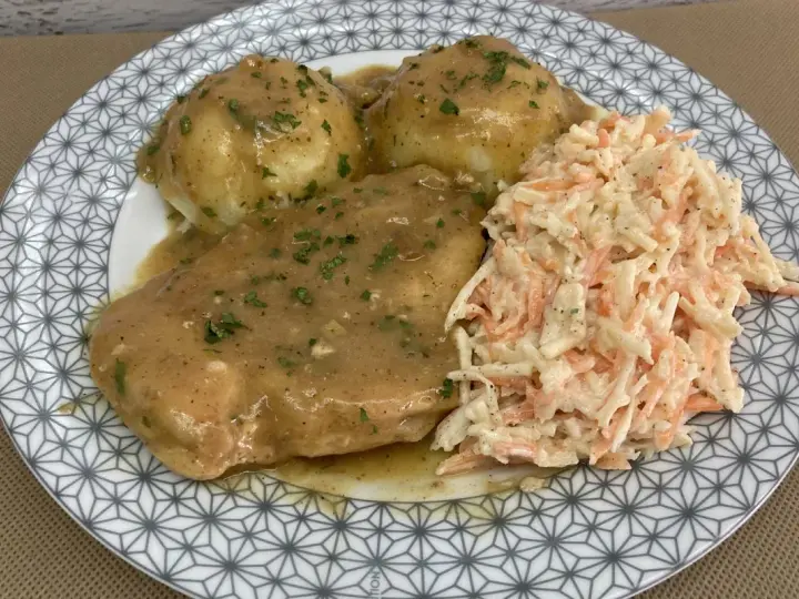 Pyszna pierś z kurczaka w sosie własnym, podana z ziemniakami i surówką z marchewki i kapusty.