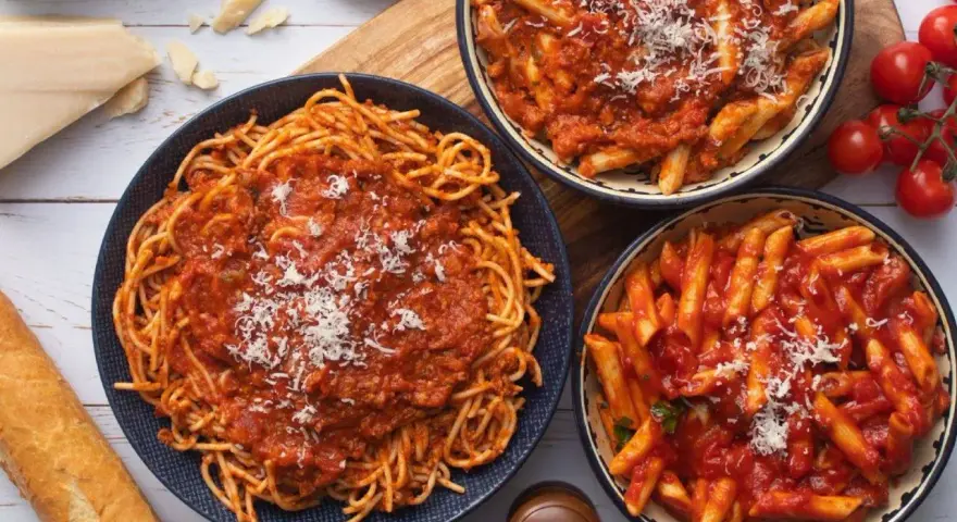 Pyszny obiad bez mięsa: spaghetti i penne w sosie pomidorowym, posypane parmezanem. Idealne dla wegetarian!