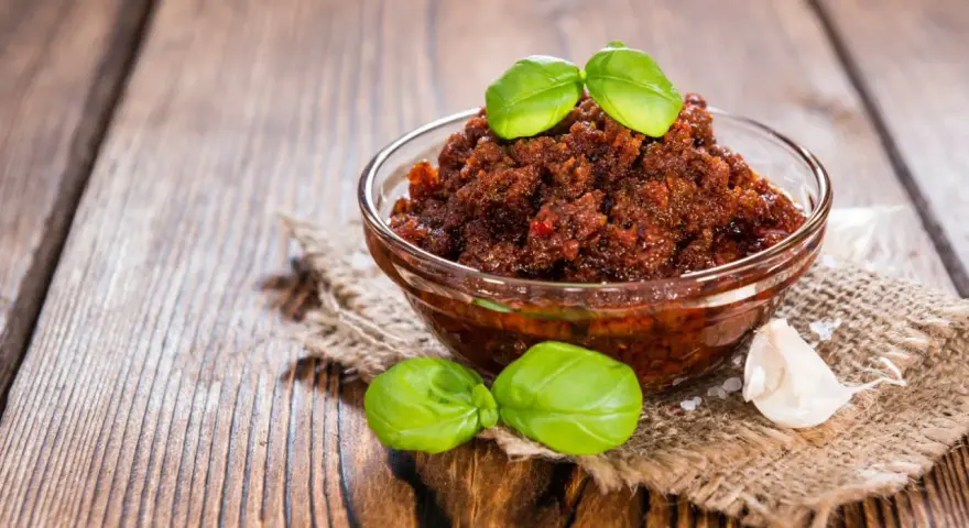 Miseczka pełna aromatycznego, czerwonego pesto z bazylią i czosnkiem, gotowa do podania.