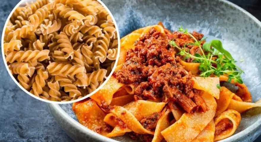 Pyszny makaron na redukcji z sosem bolognese. Widać też surowy makaron fusilli, idealny do zdrowych posiłków.