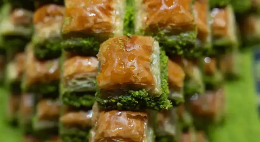 Słodka baklava, co to jest? Warstwy ciasta filo, orzechów i syropu, posypane zielonymi pistacjami. Pyszny deser!