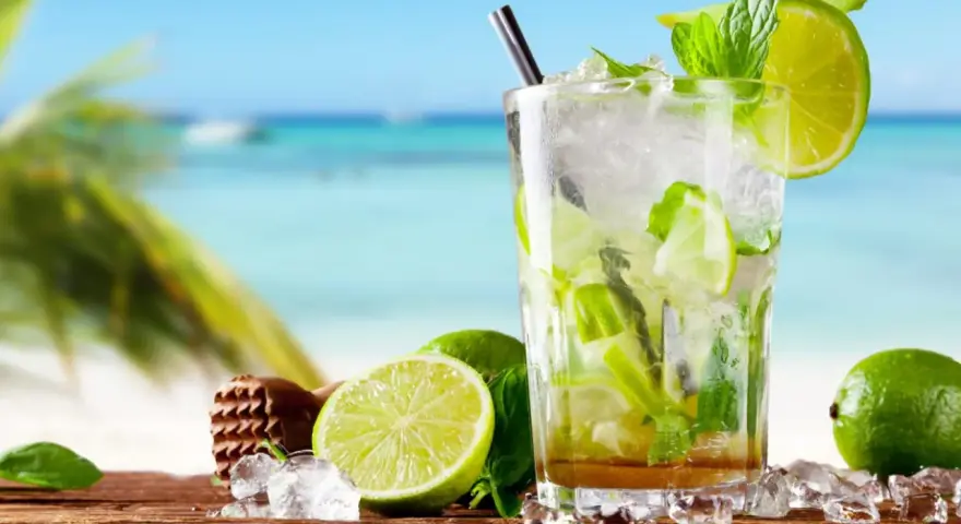 Orzeźwiający mojito na plaży, z limonkami i miętą, w tle błękitne morze i palmy. Idealny na upalny dzień.