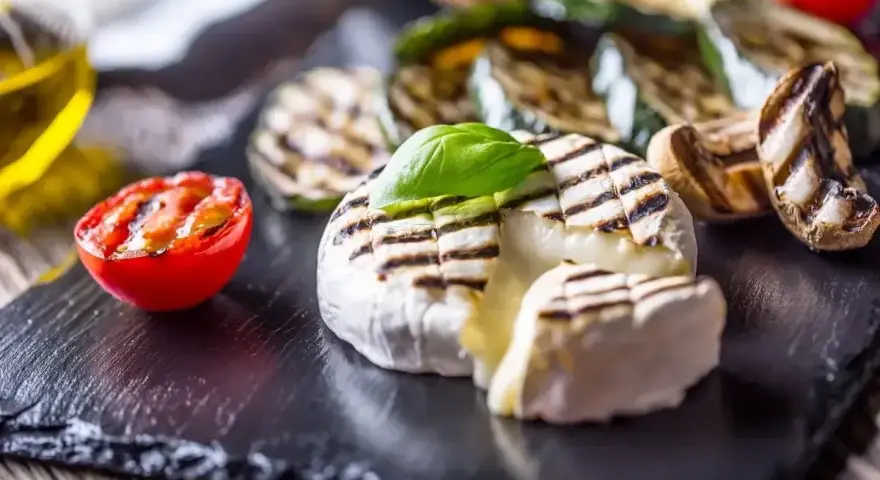Pyszny camembert z grilla, z rumianymi paskami, podany z grillowanymi warzywami i pomidorkiem. Idealny na letnie wieczory.