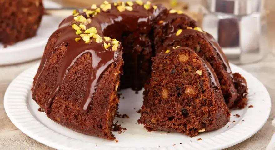 Wilgotna babka czekoladowa z orzechami, polana polewą i posypana pistacjami. Idealna na szybki deser.