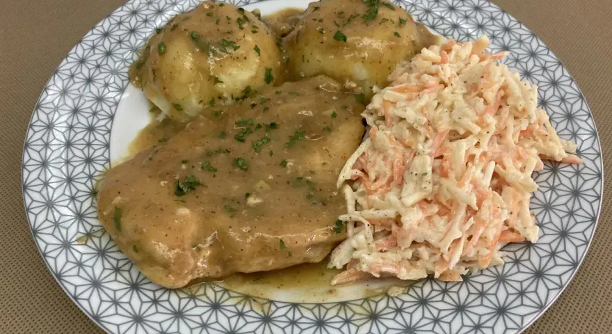 Pyszna pierś z kurczaka w sosie własnym, podana z ziemniakami i surówką z marchewki i kapusty.