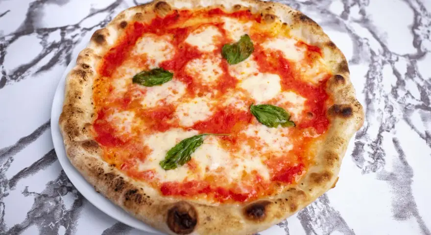 Pyszne ciasto na pizzę neapolitańską z sosem pomidorowym, mozzarellą i bazylią. Idealna na szybki lunch.