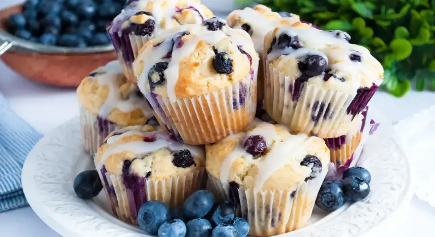 Wilgotne i puszyste muffinki z jagodami, polane lukrem. Idealne na śniadanie lub deser.