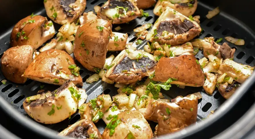 Pyszne pieczarki z airfryer, przyprawione i posypane natką pietruszki, gotowe do podania.