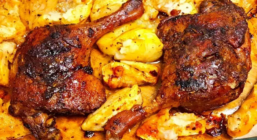 Pyszne, pieczone udka z kaczki z chrupiącymi ziemniakami, skąpane w aromatycznym sosie.