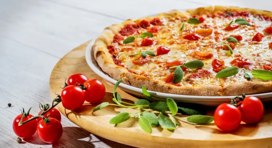 Apetyczna pizza z pomidorkami i bazylią. Czy zastanawiałeś się, dlaczego pizza jest niezdrowa?