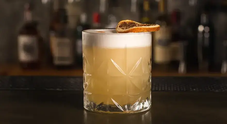Klasyczny whisky sour przepis: orzeźwiający koktajl z pianką i plasterkiem suszonej pomarańczy. Idealny na każdą okazję.