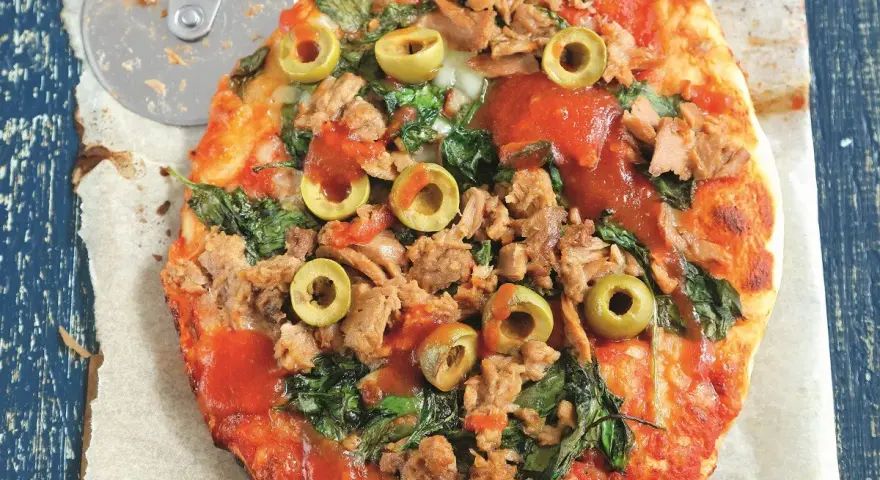 Pyszna pizza z tuńczykiem, szpinakiem i oliwkami, gotowa do pokrojenia.