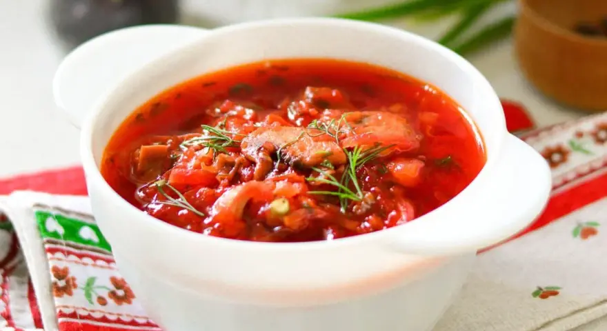 Aromaticzny barszcz ukraiński tradycyjny w białej miseczce, ozdobiony koperkiem. Idealny przepis na rozgrzewający obiad.