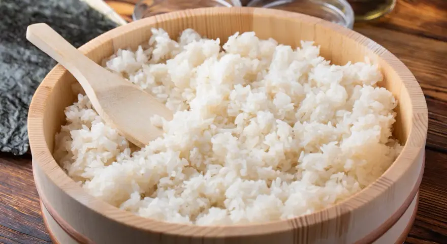 Idealny ryż do sushi, gotowy do przygotowania. Drewniana miska i łyżka sugerują tradycyjny sposób na to, jak ugotować ryż do sushi.