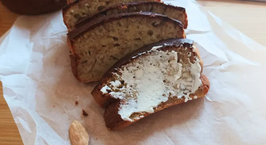 Pyszny chlebek bananowy z airfryera, pokrojony w kromki, jedna posmarowana masłem. Idealny na śniadanie.