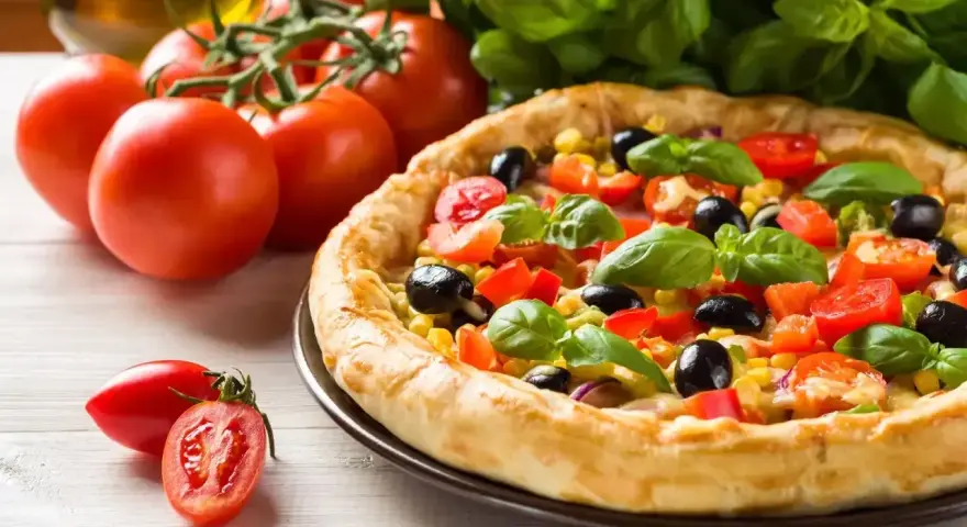 Pyszna pizza z pomidorami, oliwkami i kukurydzą, obok świeże pomidory i bazylia. Ile piec pizze?
