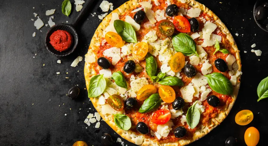 Pizza z pomidorkami, oliwkami i bazylią. Pomidorowe pesto to niezbędny dodatek smakowy włoskiej pizzy.