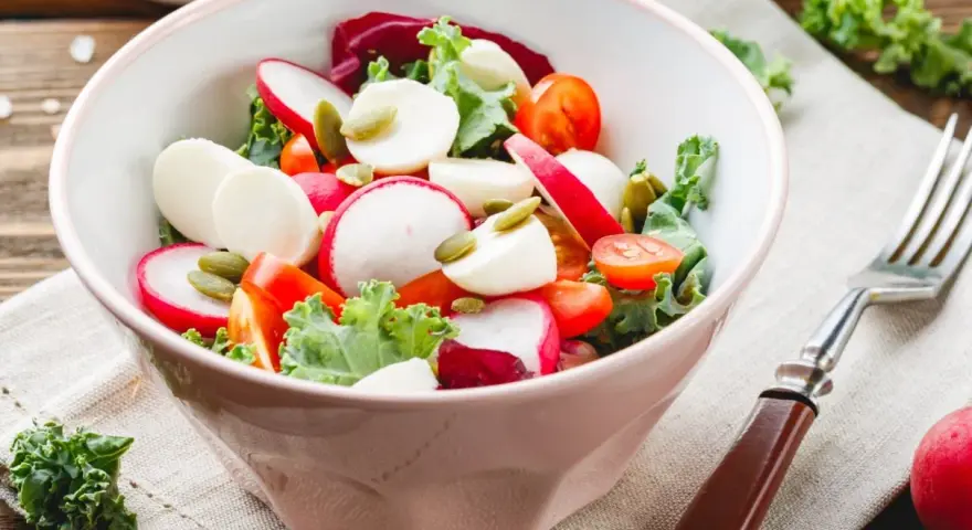Świeża sałatka do grilla w 3 minuty: rzodkiewka, pomidorki, ser mozzarella i pestki dyni w misce.