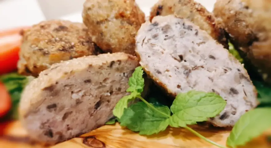 Kotleciki mielone z pieczarkami, chrupiące z zewnątrz, soczyste w środku, podane z miętą na drewnianej desce.