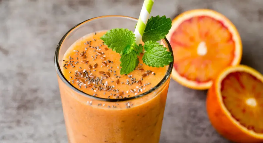 Pomarańczowy smoothie z nasionami chia i siemieniem lnianym, ozdobione miętą. Idealne na zdrowe śniadanie. Inspiracja na smoothie przepisy.