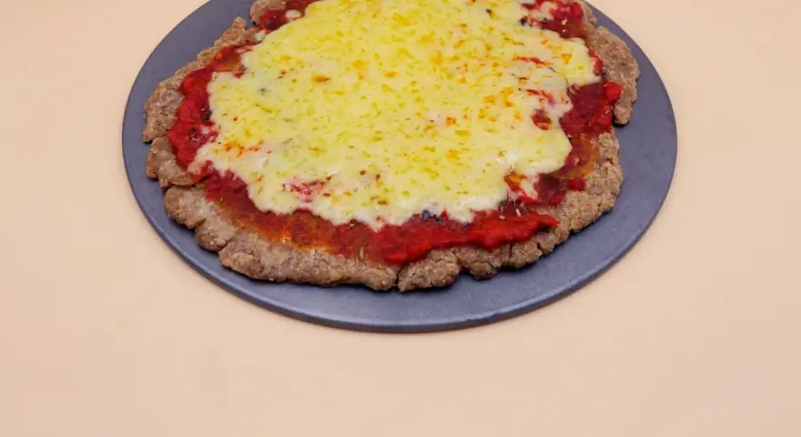 Pizza z chleba tostowego z sosem pomidorowym i roztopionym serem na ciemnej tacy.