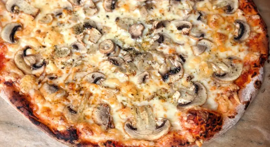 Pyszna pizza włoska z pieczarkami i ciągnącym serem. Idealny przepis na domową ucztę.