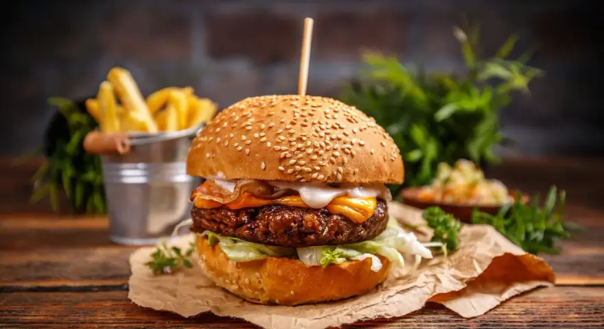 Pyszny burger z serem, bekonem i sałatą, idealny jako dodatek do frytek.