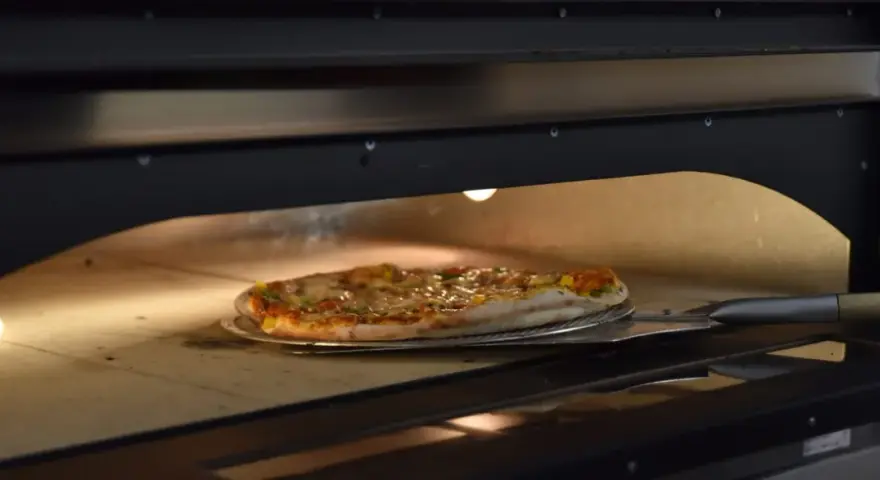 Pieczenie pizzy w piecu. Czy pizzę można zamrozić? Ta gorąca, parująca pizza na łopacie sugeruje, że świeżość jest kluczowa.