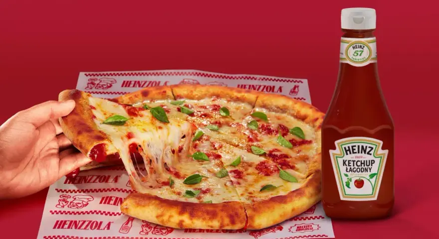 Ciepła pizza z ciągnącym serem i bazylią, obok butelka łagodnego ketchupu Heinz – idealny duet do każdego kęsa.