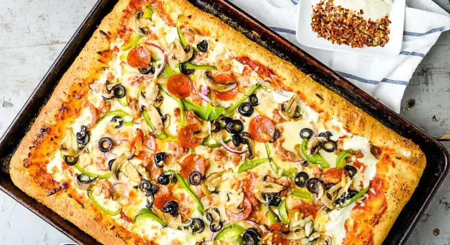 Pyszna pizza domowa na blachę z pieczarkami, papryką, oliwkami i pepperoni. Idealny przepis na szybki obiad.
